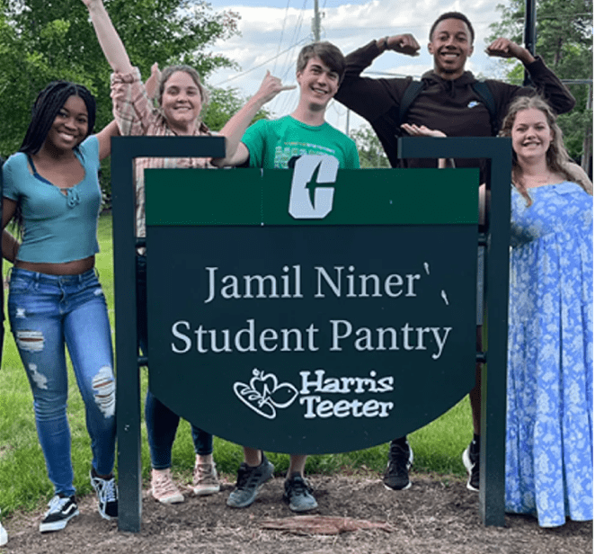 Students posing at Jamil Niner Student Pantry Sign