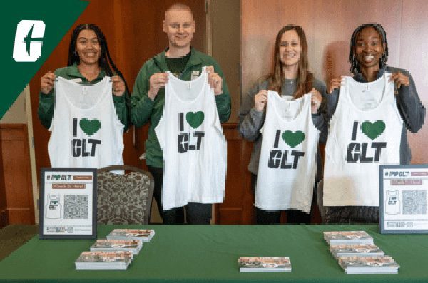 Students standing at a table holding up shirts